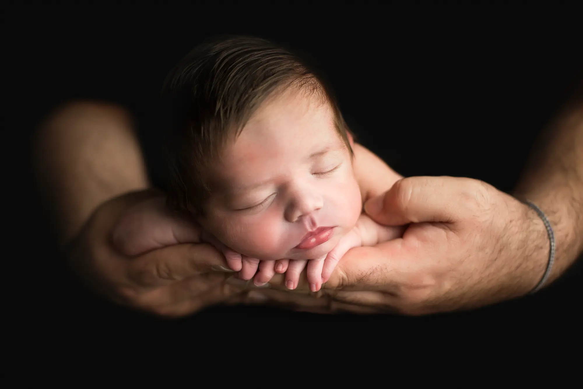 Neonato sostenuto con delicatezza durante una sessione fotografica